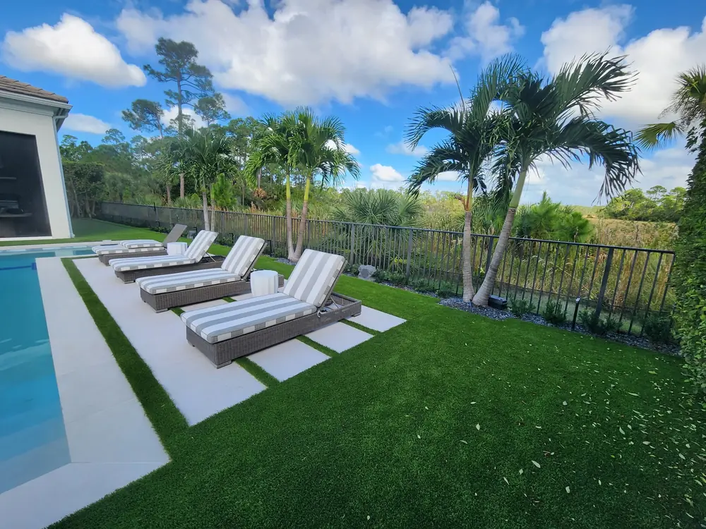 Lounge chairs on turf beside a pool overlooking a preserve